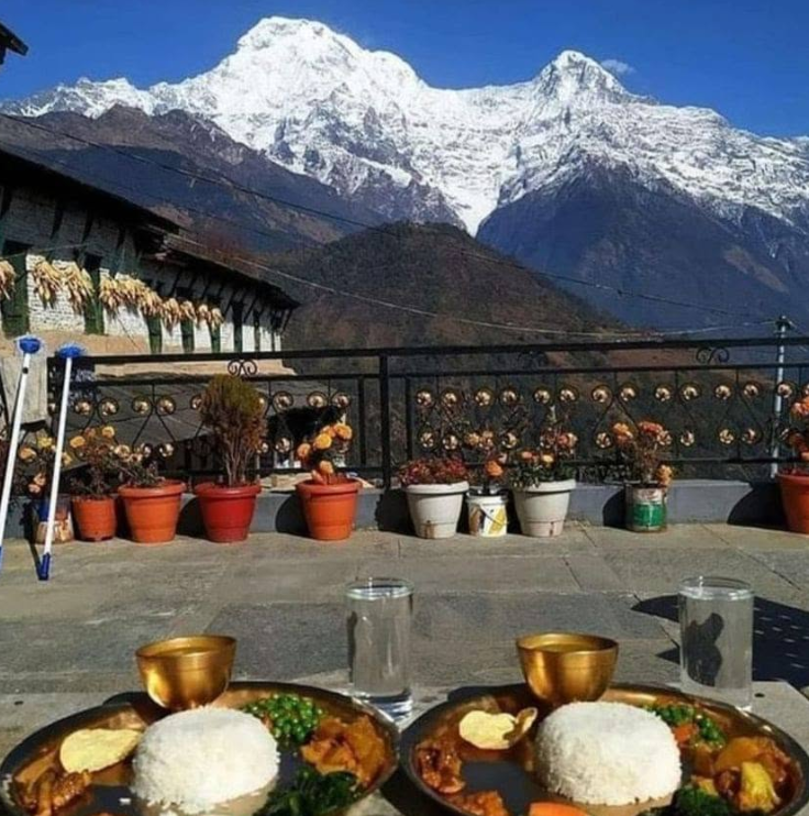 Dal bhat served on the roof terrace with the Annapurna range behind